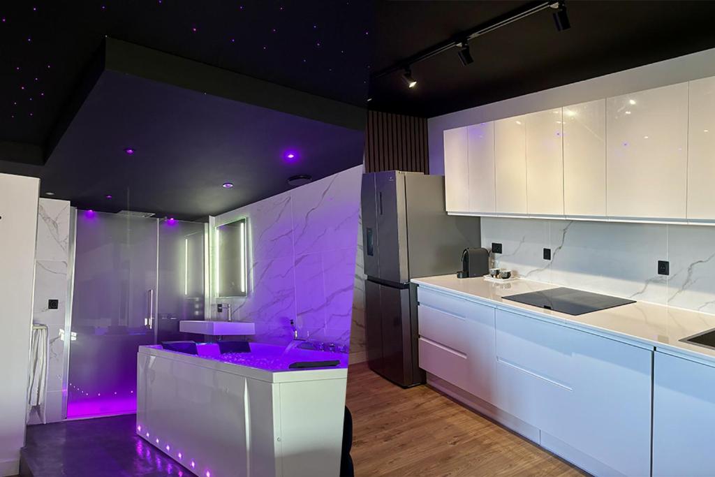 a kitchen with white cabinets and purple lighting at Penthouse Manhattan jacuzzi balneo suite luxe in Toulouse
