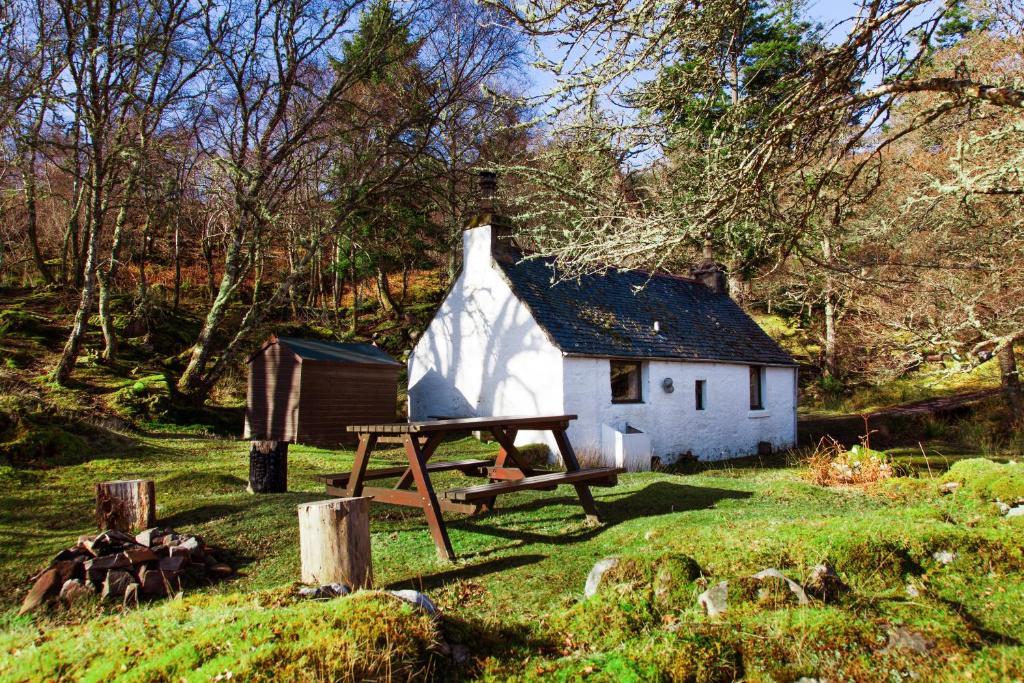 a small white house with a picnic table in front of it at Sawmill Cottage in Acharacle