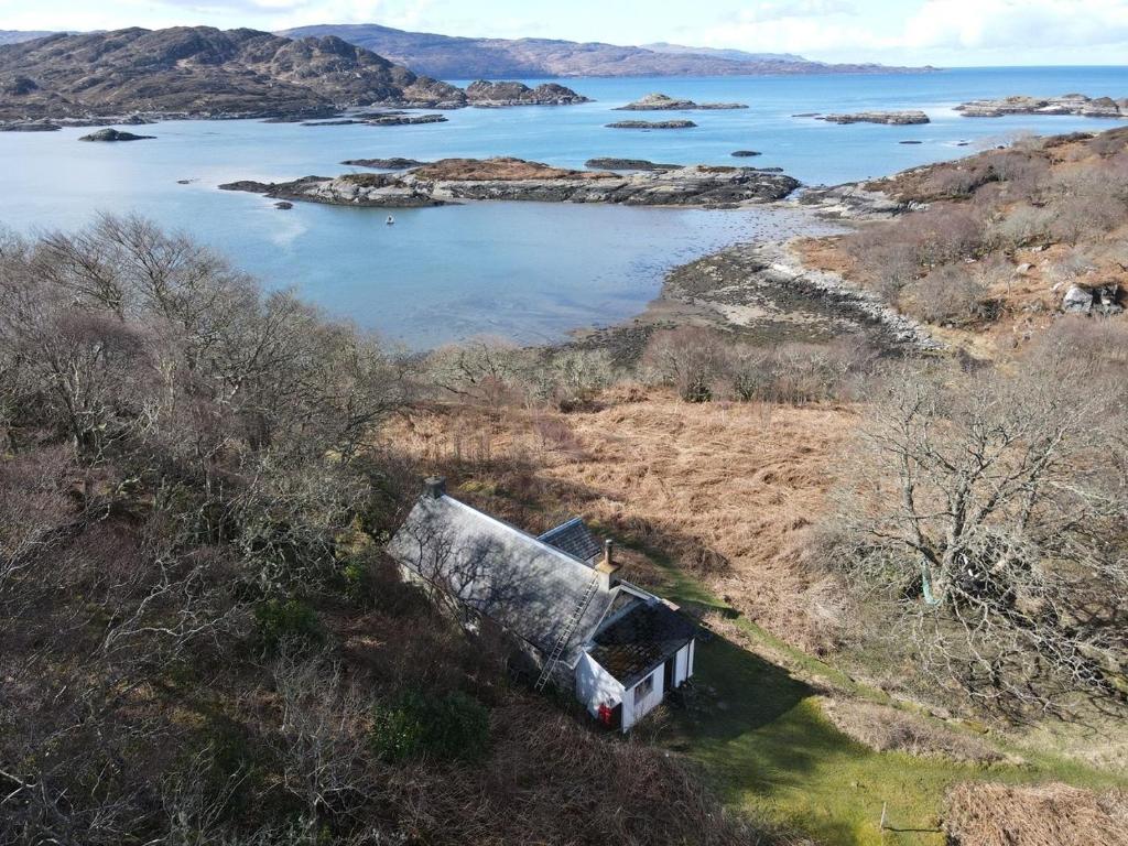 ein altes Haus am Ufer eines Wasserkörpers in der Unterkunft South Shore Cottage in Acharacle