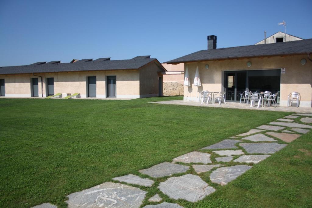 een gebouw met een gazon met stoelen en een terras bij Alojamiento Ubaldo Nieto in Carracedo del Monasterio