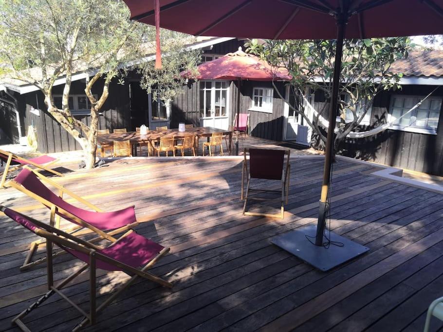 un patio avec des chaises et un parasol sur une terrasse dans l'établissement Villa de plage de caractere 12-14 pers CAP FERRET, à Lège-Cap-Ferret