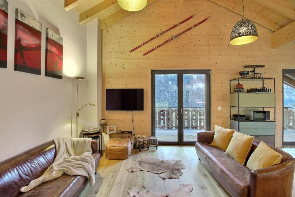 sala de estar con sofás de cuero y TV en Source 24 Penthouse Spectacular View, en Champéry