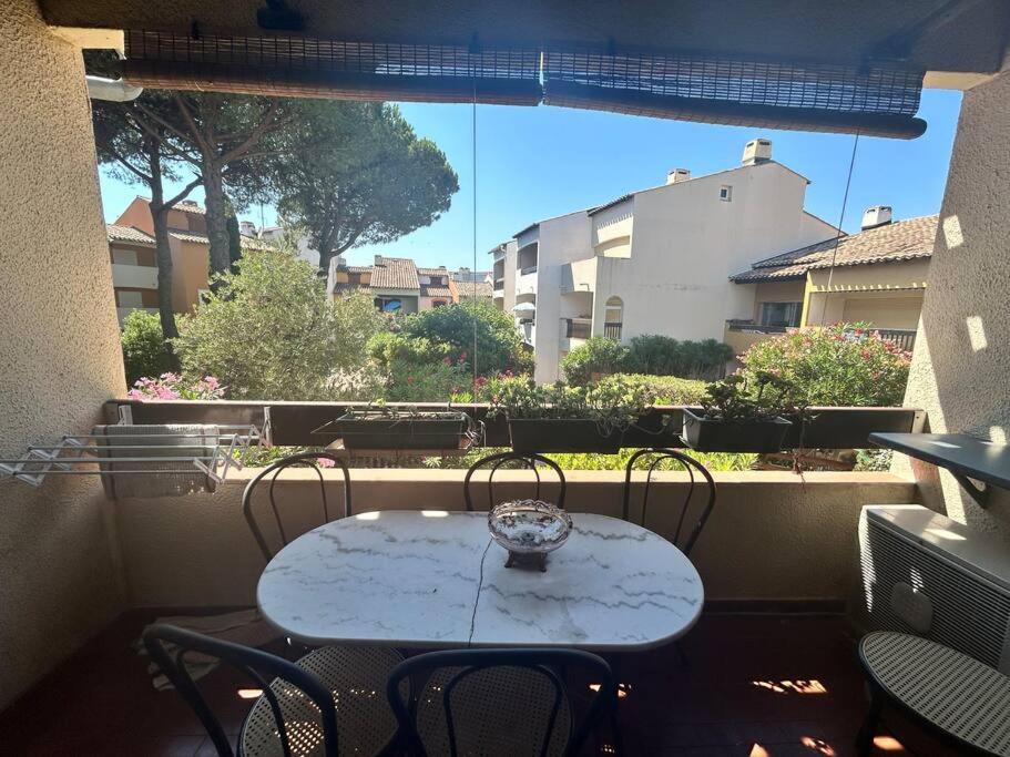 une table et des chaises sur un balcon avec une fenêtre dans l'établissement Appartement Village Camargue, au Grau-du-Roi
