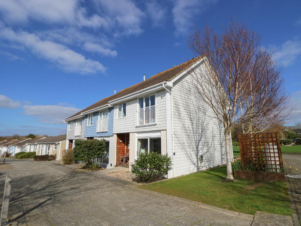 a white house with a tree next to a street at Whitfield P7 in Yarmouth