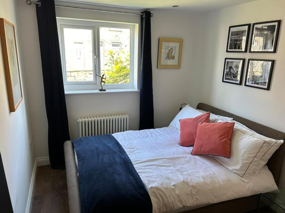a bedroom with a bed with two pillows and a window at Best rated in Barnsley- apartment sleeps 4 & 5 minute walk to town centre in Barnsley