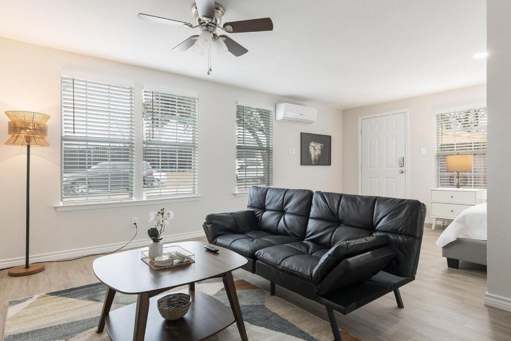 een woonkamer met een zwarte leren bank en een tafel bij Calmont Guest House in Fort Worth
