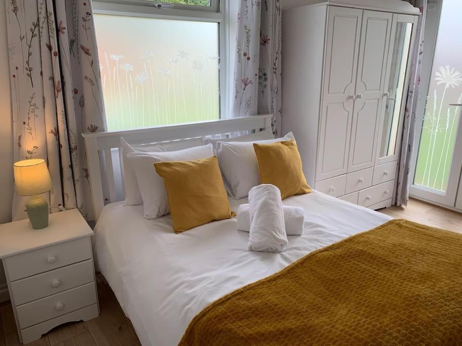 a white bed with yellow pillows and a window at Modern, Stylish lodge with Paddock Views in Sandwich