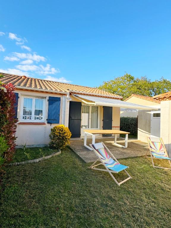 deux chaises et une table devant une maison dans l'établissement Chez Karine et Rodolphe La Cosy, piscines, plage, à Saint-Michel-Chef-Chef