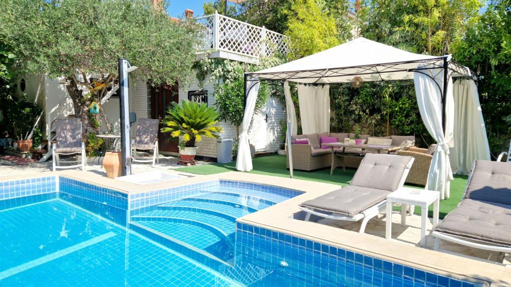 a swimming pool with chairs and a gazebo at Avalena Residence in Zadar