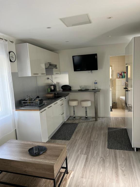 une cuisine avec des armoires blanches et une télévision à écran plat dans l'établissement Maisonnette atypique, à Crégy-lès-Meaux