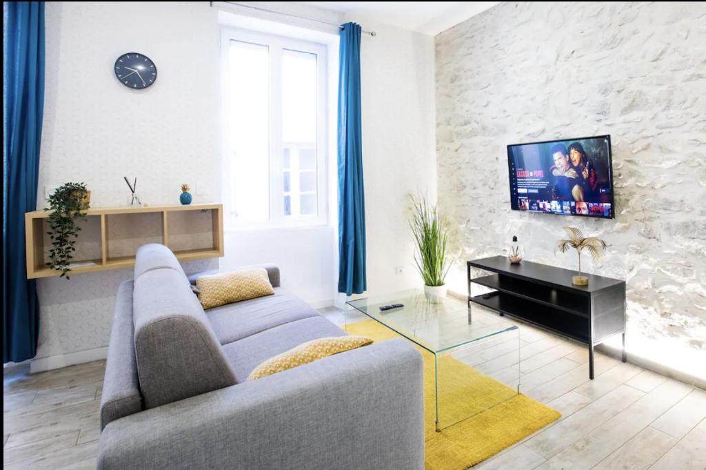 un salon avec un canapé et une télévision dans l'établissement 2 pièces centre-ville tout équipé, à Nîmes