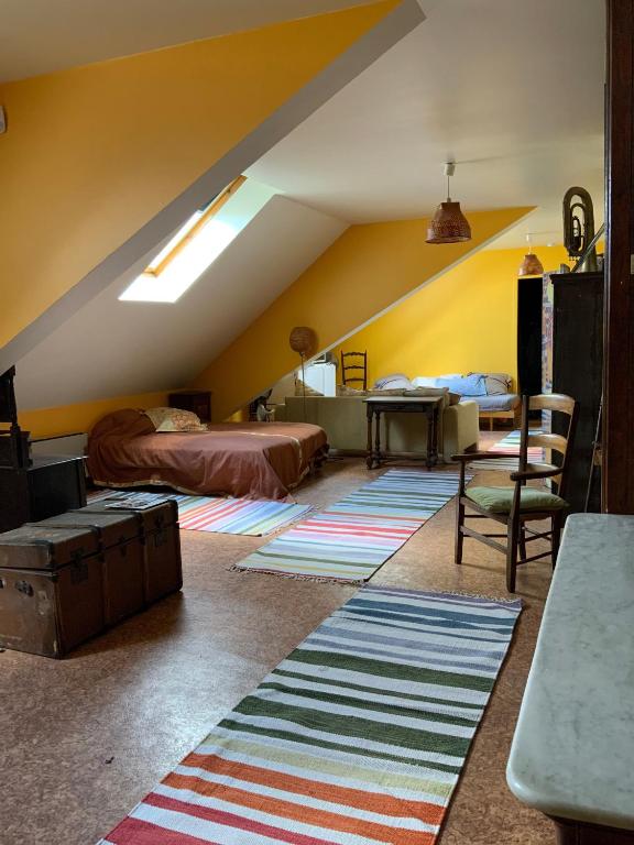 une chambre mansardée avec un lit, une table et un tapis dans l'établissement STUDIO 63M2 3EME ETAGE OU CHAMBRE DANS APPARTEMENT 2EME ETAGE pour SEJOURS A MOULINS, à Moulins