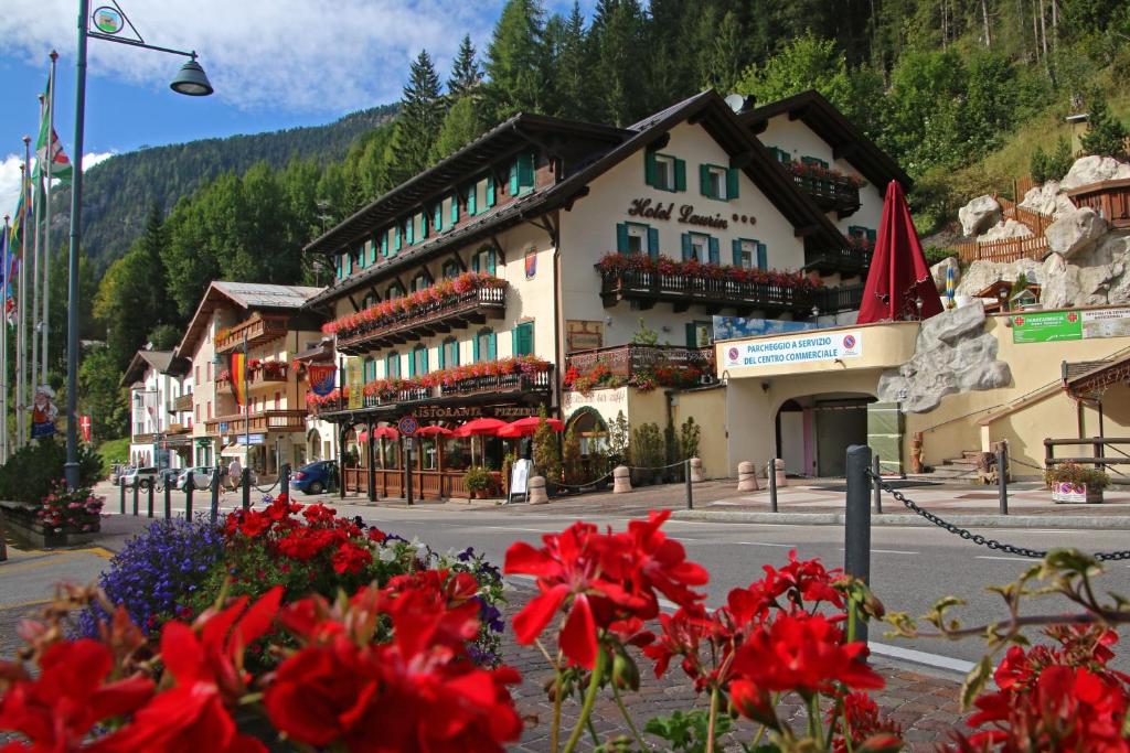 un edificio con fiori rossi di fronte a una strada di Hotel Laurin a Canazei