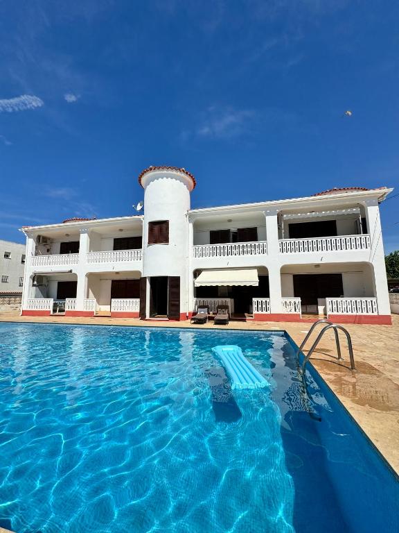 a hotel with a swimming pool in front of a building at Apartment Tres Palmeras with pool in Vinarós
