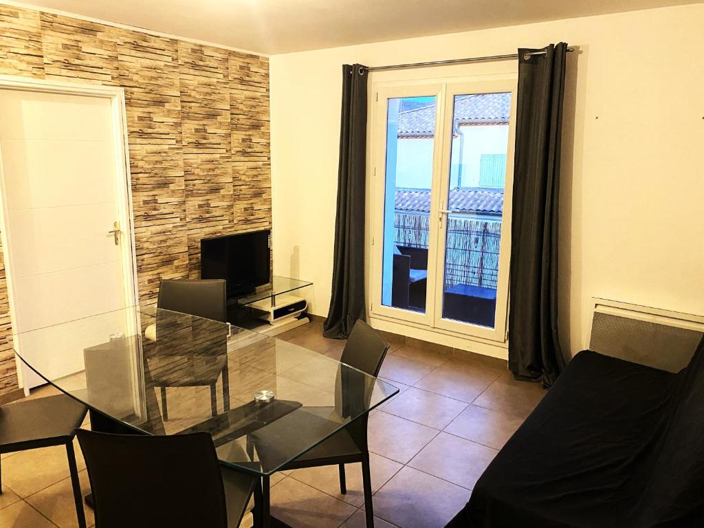 un salon avec une table en verre et des chaises dans l'établissement Charmant T2 calme centre ville, à La Crau