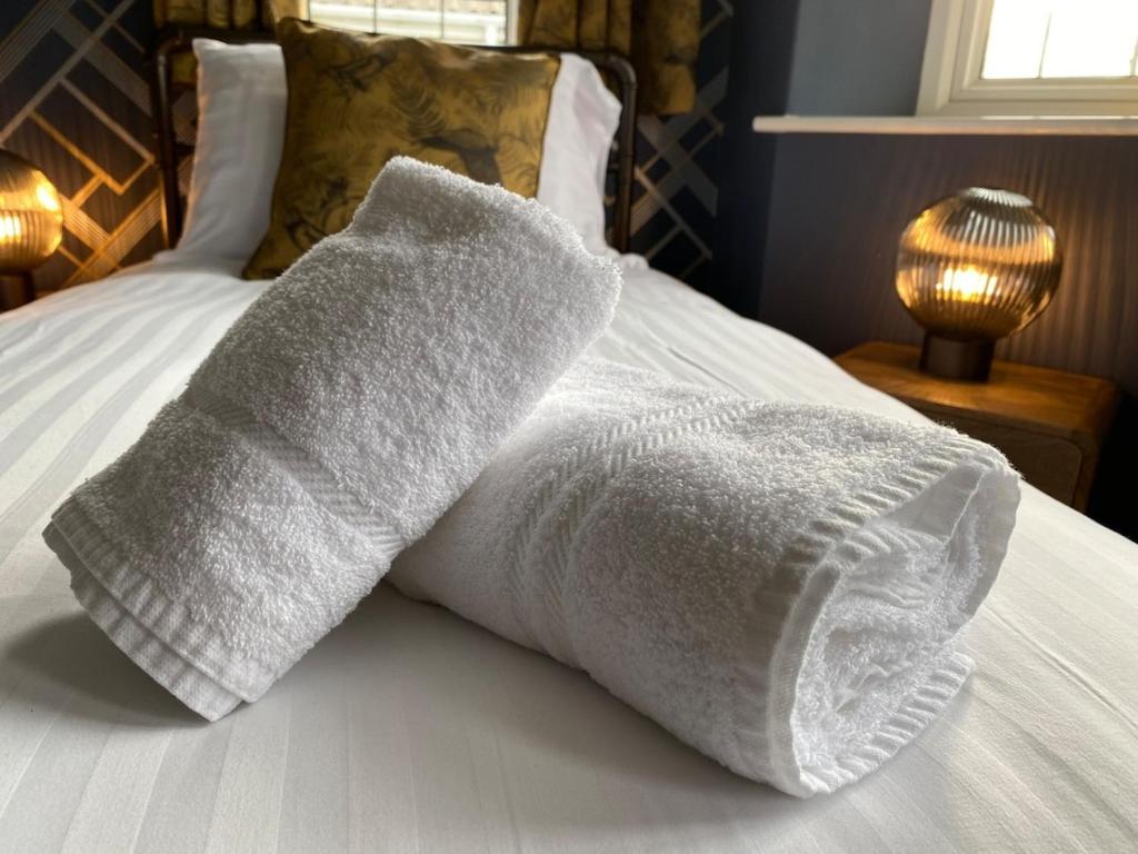 a pile of towels on a bed with a lamp at Eclectic Bungalow Parking Nr Beach in Kent