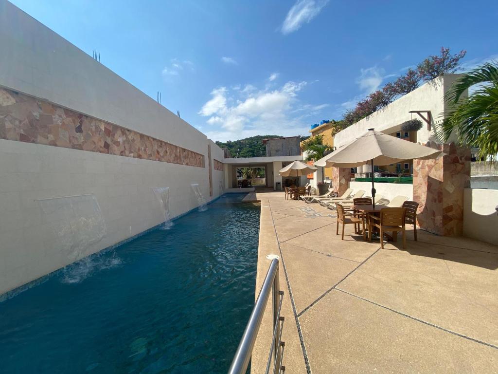 - une piscine avec des tables et des chaises à côté d'un bâtiment dans l'établissement AMPARO RESORT, à Los Ayala