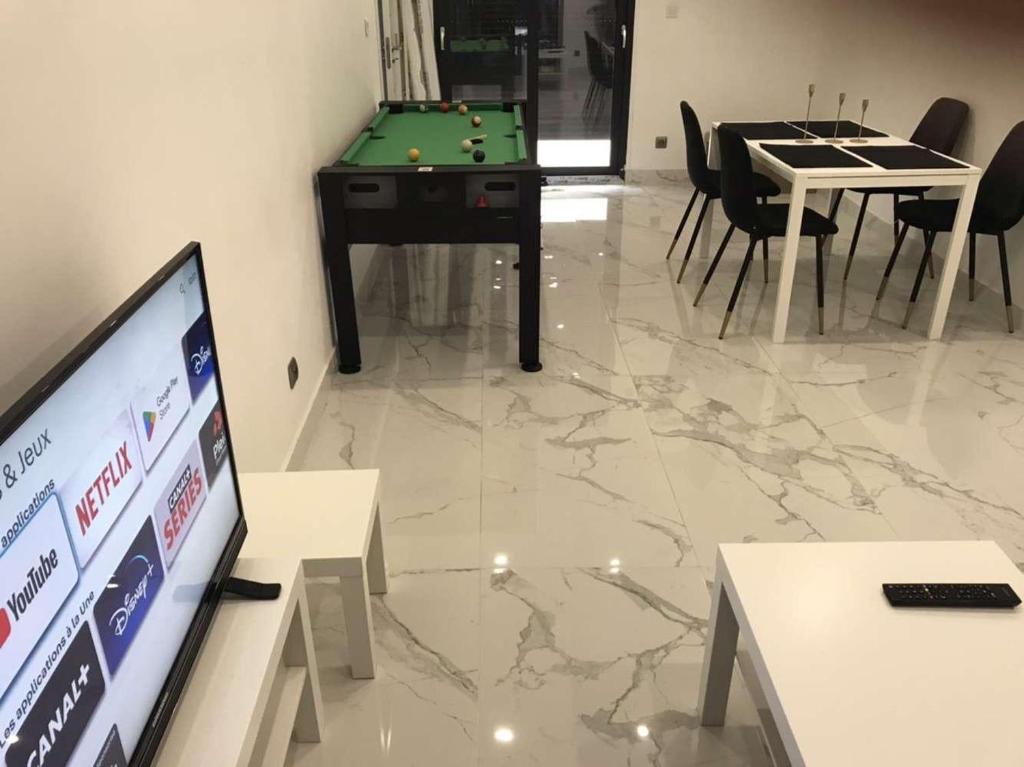 un salon avec une télévision et une table avec un billard dans l'établissement Ali, à Savigny-le-Temple