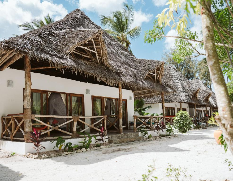 a house on the beach with a thatched roof at Bahati Sunset Bungalows Michamvi in Michamvi