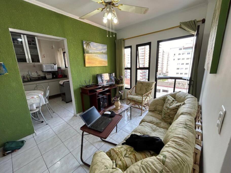 un salon avec un canapé et un ordinateur portable sur une table dans l'établissement Lindo Apto 502 em PG Ocian, à Praia Grande