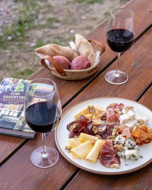 a plate of food and two glasses of wine on a wooden table at Villa Mansa in Vistalba
