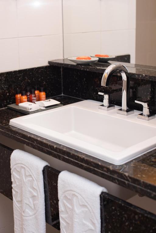 a bathroom counter with a white sink and towels at Sol Ipanema Hotel in Rio de Janeiro