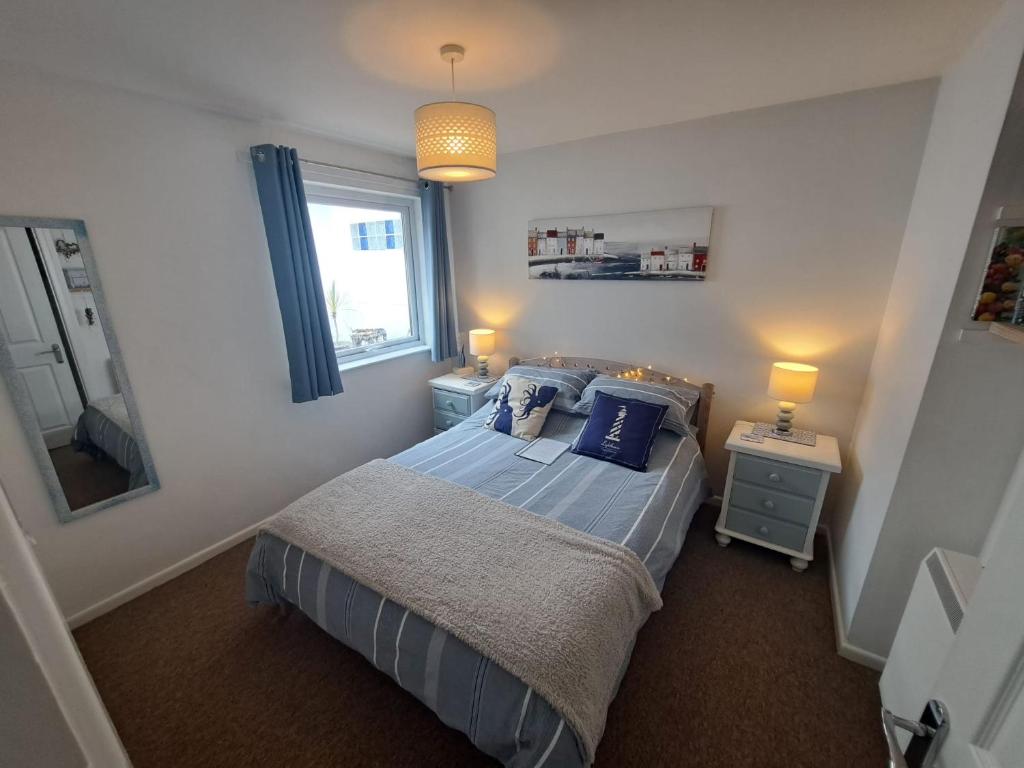 Un dormitorio con una cama con almohadas azules y una ventana. en Willow Bungalow Quiet and secluded, en Carbis Bay