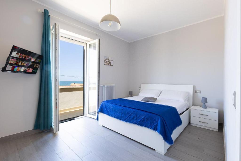une chambre blanche avec un lit et une grande fenêtre dans l'établissement SUNSET BEACH, à Fiumicino