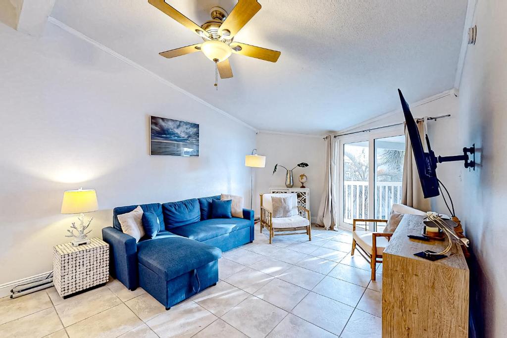 a living room with a blue couch and a ceiling fan at Sand Dollar E201 in Pensacola Beach