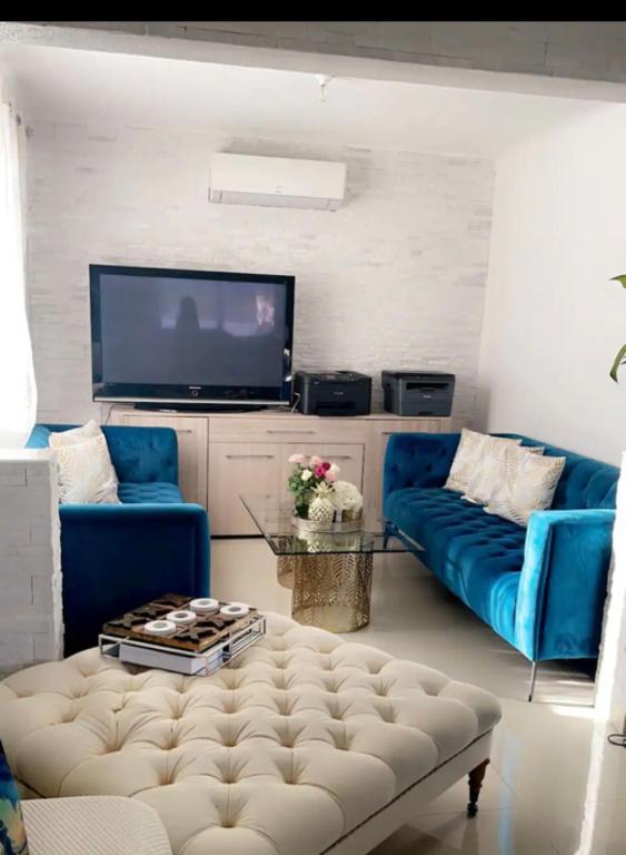 un salon avec un canapé bleu et une télévision dans l'établissement Maison Laurier 3 chambres, à Bagnols-sur-Cèze