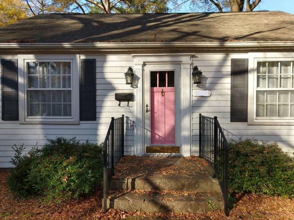 a white house with a pink door on it at Charming Classic Cottage 2Br in Durham