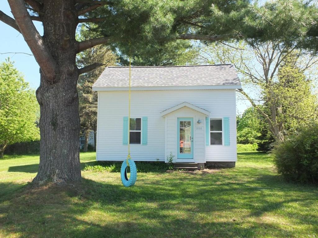 a small white house with a blue swing in a yard at Beach Town Escape - Newly-remodeled & Gorgeous! in Frankfort