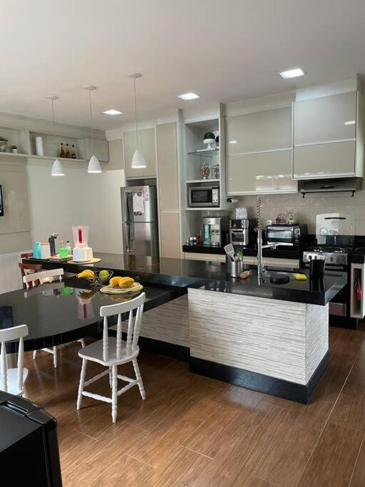 a kitchen with a black counter top and a table at Chácara Jatobá in Espirito Santo Do Pinhal