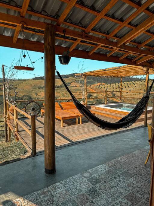 a hammock on a wooden deck with a view of a field at Cabanas do Paiol Texas Cabin Toledo MG in Toledo