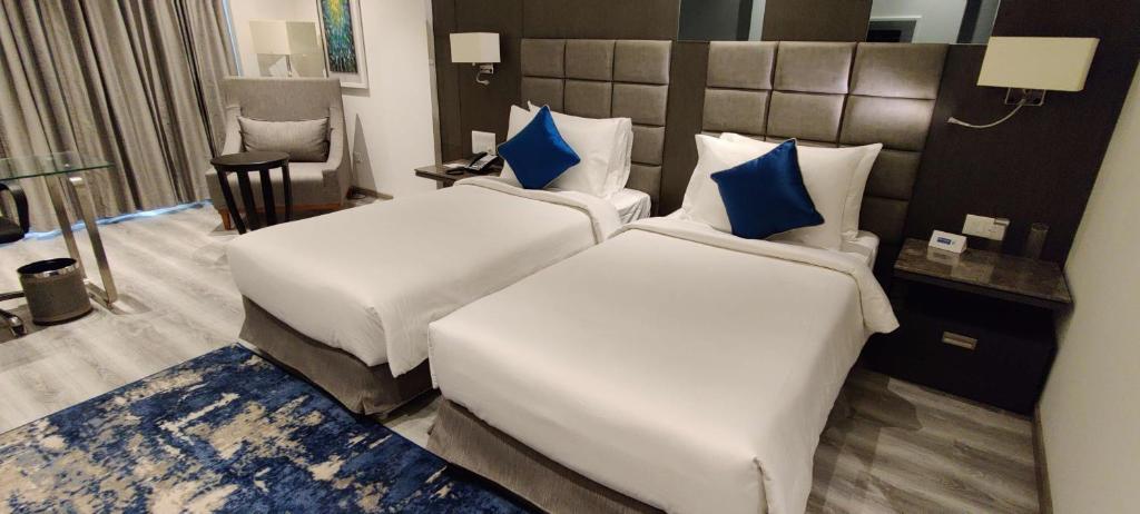 a hotel room with two beds with blue pillows at Best Western Plus Tejvivaan in Visakhapatnam