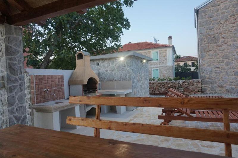 a outdoor grill with a table and a bench at Apartman Iris in Gabonjin