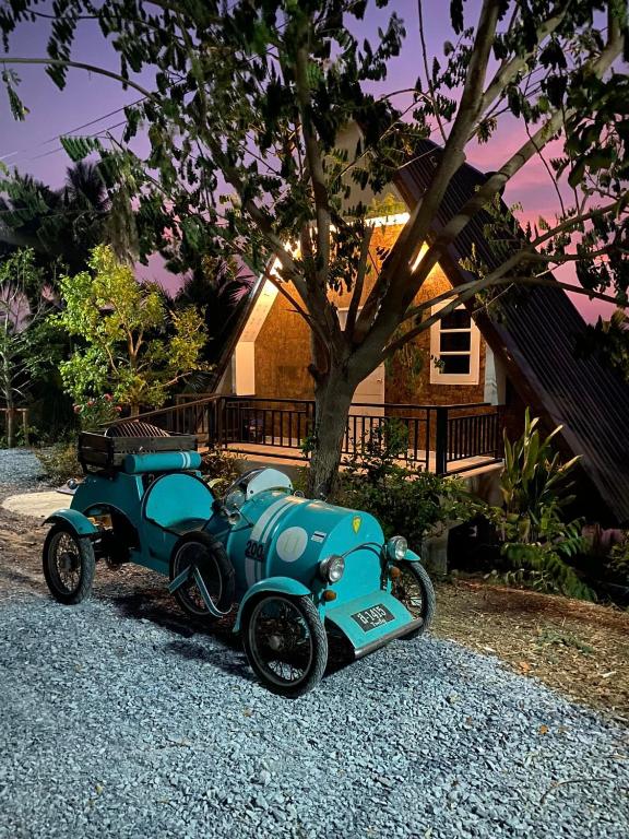 una piccola auto blu parcheggiata di fronte a una casa di ไร่ณัฐลิษา โฮมสเตย์ a Ban Plai Nam