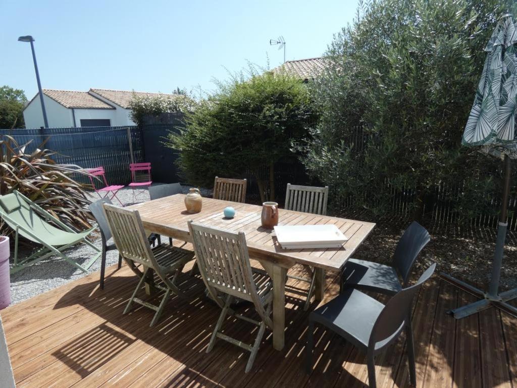 une table et des chaises en bois sur une terrasse en bois dans l'établissement Maison spacieuse avec jardin clos, près plage, animaux OK, 10 pers, Notre-Dame-de-Monts - FR-1-540-137, à Notre-Dame-de-Monts