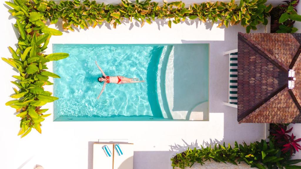 a person swimming in a pool in a mirror at Sonnys Uluwatu in Uluwatu