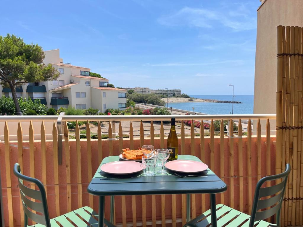 - une table avec une bouteille de vin et une pizza sur le balcon dans l'établissement Studio refait en 2024 avec terrasse, climatisation et parking, à 50m de la plage - FR-1-338-588, à Sète