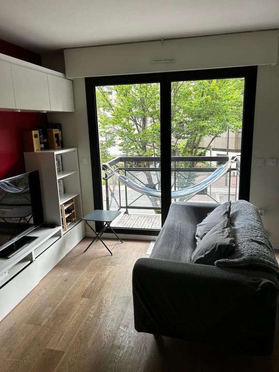 un salon avec un canapé et une grande fenêtre dans l'établissement Appartement Zen, à Bourg-la-Reine
