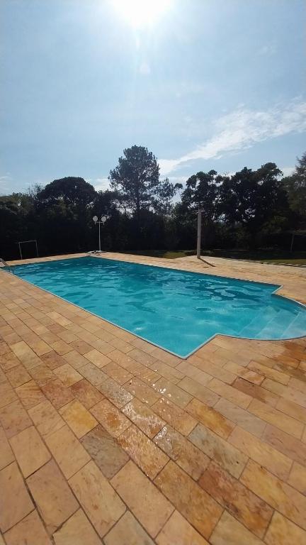 a swimming pool with blue water in a yard at Casa da Felicidade in Ibiúna