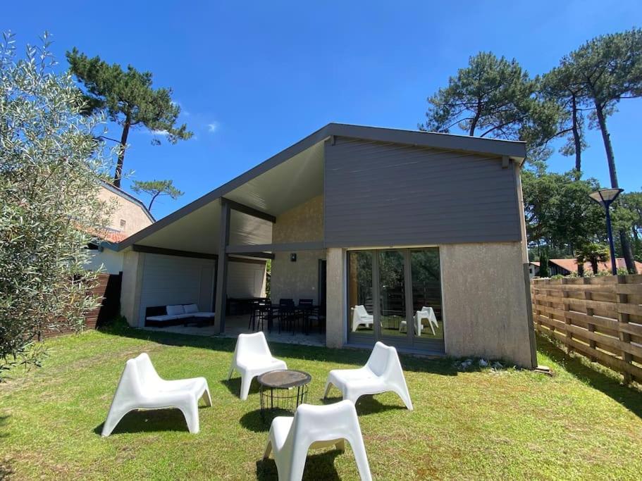 un groupe de chaises blanches devant une maison dans l'établissement Maison 6 pers 3 Chb avec jardin, proche Golf Hossegor, à Capbreton