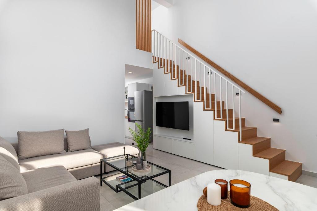 a living room with a couch and a staircase at Calliope luxury loft with backyard in Ierápetra