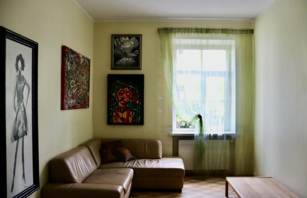 Una sala de estar con un sofá y una ventana. en Green House Apartment, en Kaunas
