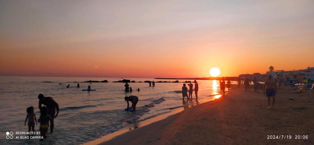 eine Gruppe von Menschen am Strand bei Sonnenuntergang in der Unterkunft DonnaLory in Donnalucata