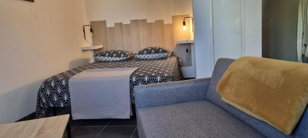 une petite pièce avec un lit et un canapé dans l'établissement Jardin des oiseaux, à Narbonne