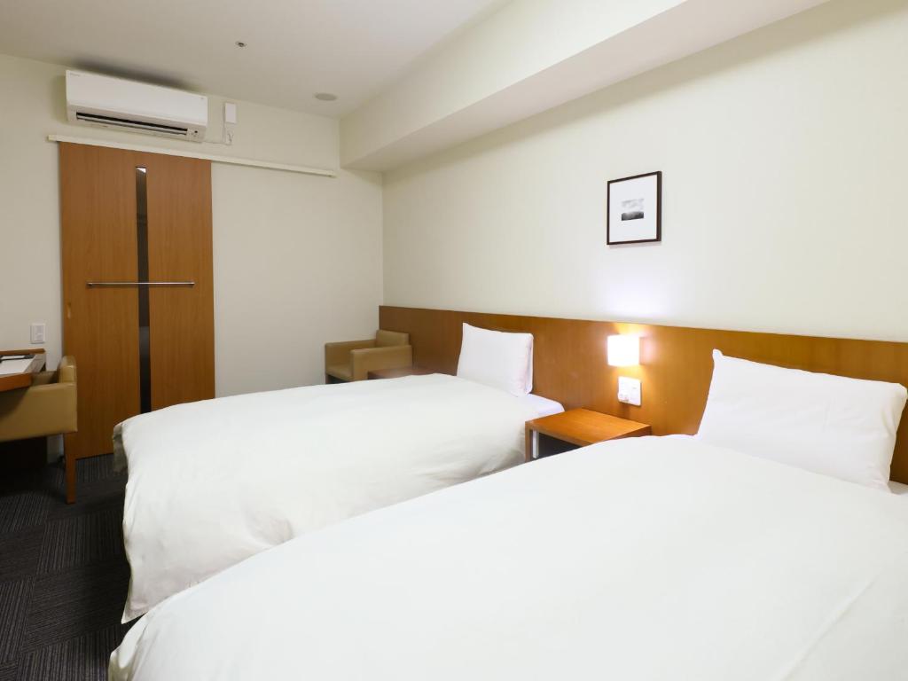 a hotel room with two beds and a tv at Dormy Inn Kanazawa Natural Hot Spring in Kanazawa