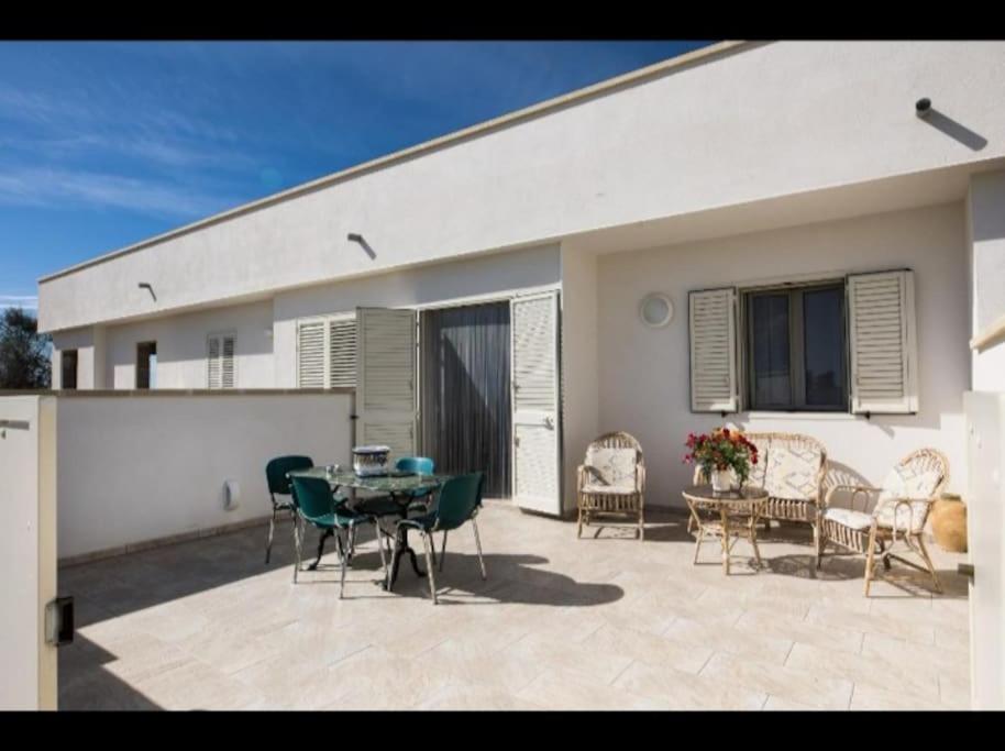 un patio con tavolo e sedie e un edificio di Casa Relax Torre Pali a Torre Pali