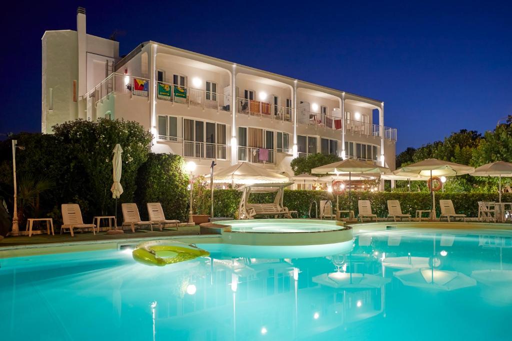 a pool in front of a hotel at night at Baby Gigli in Numana